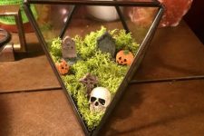 a mini Halloween cemetarium with moss, mini pumpkins, tombstones and a skull is an easy to repeat solution