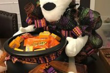 a mummy holding a witch’s cauldron with sweets and candies is a great idea for styling your porch at Halloween