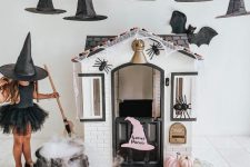 a playhouse with pink pumpkins, witches’ hats over it and a cauldron, spiders and layered rugs