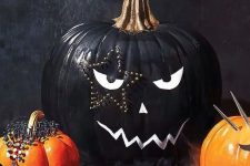a stylish black and white Halloween pumpkin with a face and a star-shaped tattoo done with decorative pins