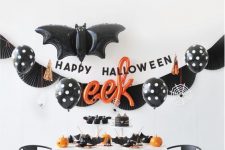 a stylish black, white and orange Halloween space with black balloons, orange pumpkins and black napkins and plates