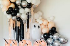 kids’ Halloween party decor with peachy, black and white balloons, BOO letters and a disco ball