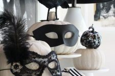 white pumpkins with chic decor – black embellished masks and feathers are amazing for Halloween and are very easy to make