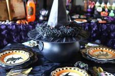 witches-inspired table decor with printed plates, a cauldron covered with a witch’s hat with spiders is cool for Halloween