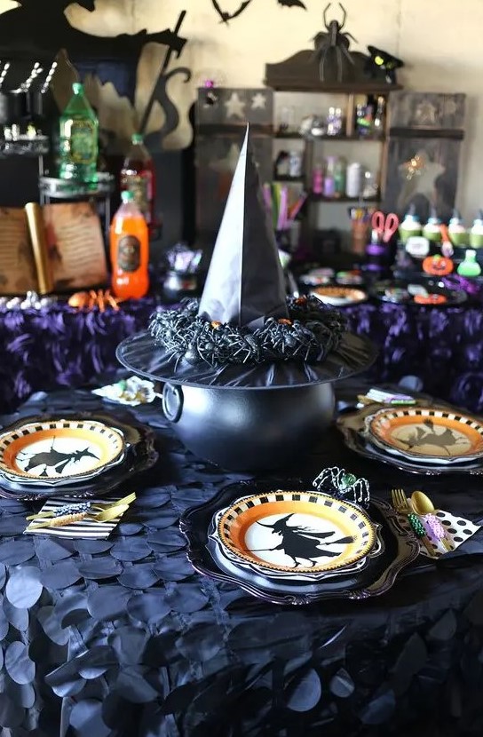 witches-inspired table decor with printed plates, a cauldron covered with a witch's hat with spiders is cool for Halloween