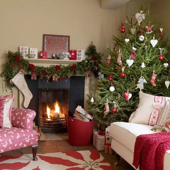 A Christmas tree with red and white ornaments, a garland with red blooms and gift boxes make the space feel Scandinavian and holiday like