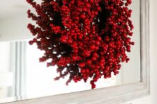 a Christmas wreath composed of red ornaments and faux berries looks very bold, eye-catchy and super cool