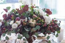 a beautiful and natural Thanksgiving centerpiece of usual and dark foliage, white pumpkins, berries and white blooms