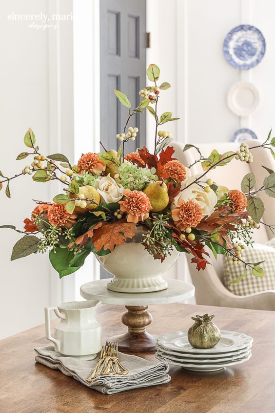 a beautiful and refined Thanksgiving centerpiece of white, orange blooms, berries, greenery, green hydrangeas and pears