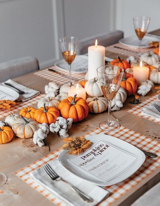 a bold Thanksgiving centerpiece of white and orange mini pumpkins, cotton and pillar candles is a pretty solution for a rustic Thanksgiving tablescape