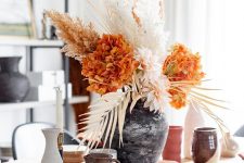 a bold and cool Thanksgiving centerpiece of blush and orange blooms, dried leaves and grasses is awesome