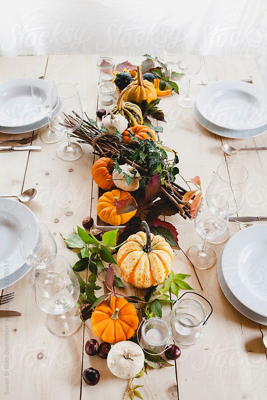 a bold rustic Thanksgiving centerpiece of pumpkins, fruits, greenery, branches and candles is a very cool and bold idea