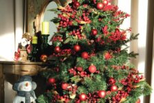 a bright Christmas tree styled with red ornaments and faux berries plus pinecones looks amazing