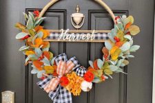 a bright Thanksgiving wreath of a hoop with faux leaves, berries, plaid ribbon and some mini colorful gourds is amazing