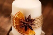 a candle with twine, a dried fruit slice and a spice piece is a gorgeous idea for fall or winter and it provides cool aroma