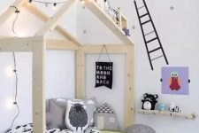 a cozy and fun Scandinavian kids’ room with a wooden house-shaped bed, a shelf, some bright artworks and toys and stars on the walls