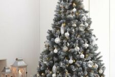 a delicate neutral Christmas tree decorated with white, silver and semi sheer ornaments, lights and a lit up star tree topper