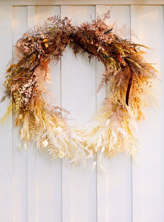 A fantastic ombre Thanksgiving wreath of dried leaves, herbs, greenery and some berries looks jaw dropping and strikes with color