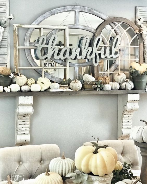 a faux Thanksgiving mantel with small neutral pumpkins, lots of window frames and a mirror plus a sign of metal