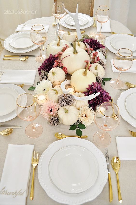 a gorgeous Thanksgiving centerpiece of white, blush and purple blooms, antlers and white pumpkins plus candles is a very bold and chic idea