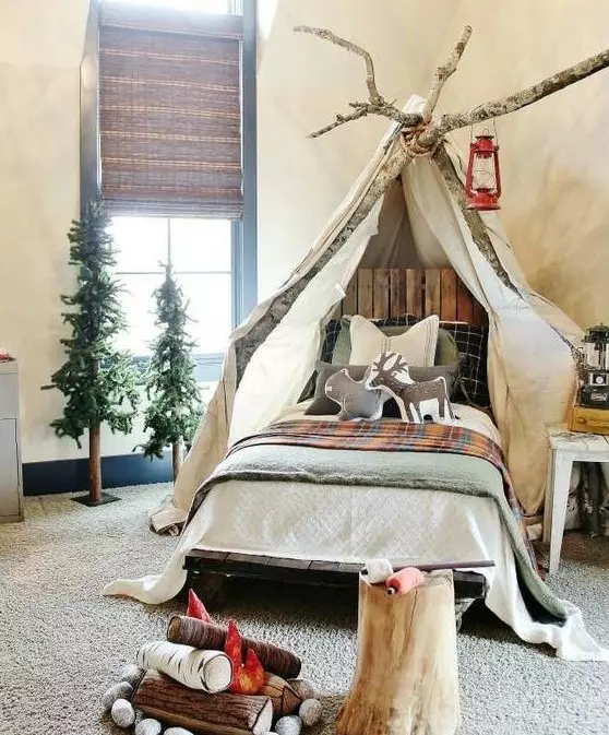 A gorgeous camp themed kids' room with canopy on branches, woven shades, faux trees and a faux fireplace