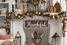 a gorgeous vintage Thanksgiving mantel with a lush dried leaf, pumpkin and wheat garland and wreath, wooden pumpkins and candles