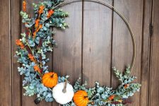 a large and bold fall or Thanksgiving wreath with faux greenery, blooms and a trio of bold pumpkins is a lovely idea