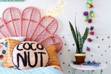 a lovely bright kid’s room with a bed with a pink peacock headboard and colorful bedding, a polka dot wall, colorful decor and books