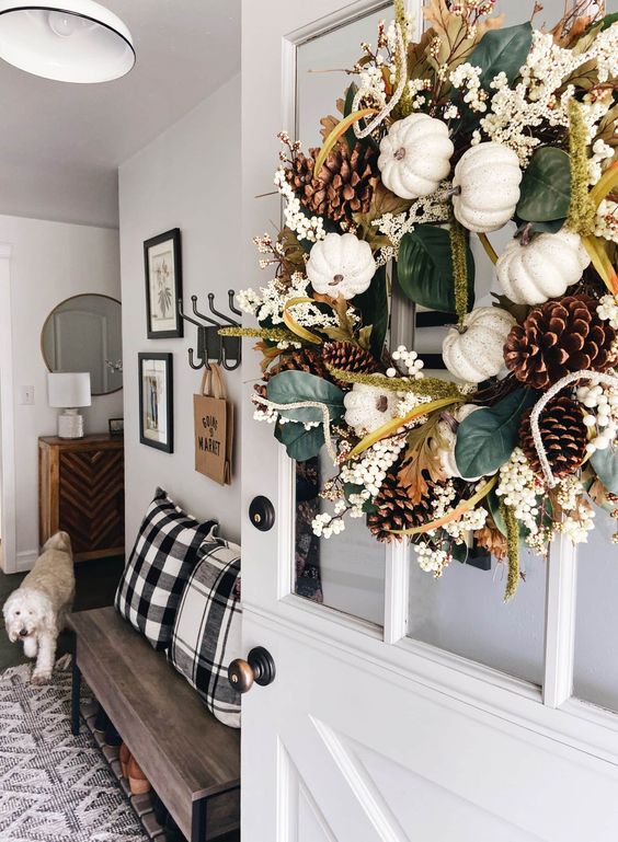 a lovely fall or Thanksgiving wreath with leaves, berries, white pumpkins and pinecones is a stylish decoration