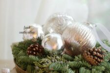 a metal tray with evergreens, silver ornaments and pinecones is a cool Christmas centerpiece idea