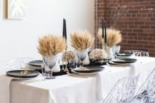 a modern farmhouse Thanksgiving centerpiece of wheat in jugs and black candles in tall gilded candleholders