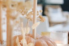a natural pumpkin with a tall and thin candle and lots of grasses plus candles around is a cool decor idea for Thanksgiving