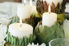 a neutral Thanksgiving centerpiece of pillar candles wrapped with fresh veggies and white blooms is a creative solution