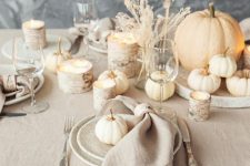 a neutral and natural Thanksgiving centerpiece of mini gourds, dried grasses, candles in birch bark candleholders