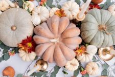 a pretty and natural Thanksgiving centerpiece of some pumpkins, small and large ones, bold blooms and tall and thin candles