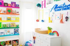 a rainbow-inspired kid’s room with colorful ledges and books, a bold gallery wall, a green leather rocker, a colorful pouf