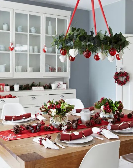 a red and white Christmas chandelier, a red table runner and berries for decor create a holiday atmosphere