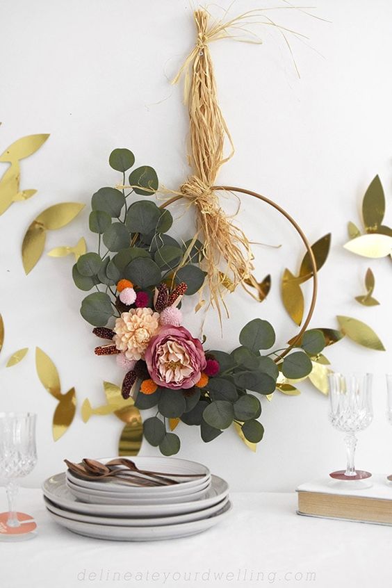 a refined and cute boho Thanksgiving wreath with greenery, pink and blush blooms and some hay is a cool idea to try