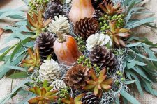 a rustic Thanksgiving centerpiece of greenery, sucuclents, pinecones and gourds is a lovely idea for a party