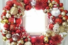 a shiny Christmas wreath fully made of ornaments, in gold, silver and red, of various sizes and looks