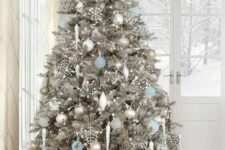 a silver Christmas tree decorated with white, silver and light blue ornaments, rhinestone snowflakes and lights plus a snowflake topper