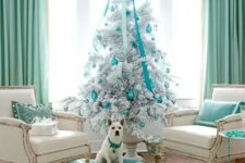 a silver Christmas tree with silver and turquoise ornaments and ribbons and a large suspended bow over the tree