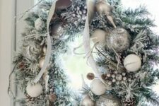 a silver Christmas wreath with snowy pinecones and a bow on top is a chic idea for Christmas decor