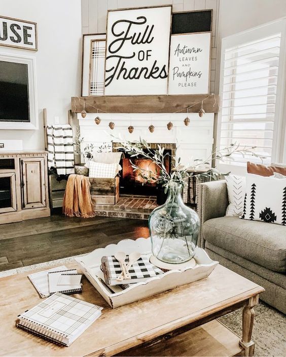 a simple farmhouse Thanksgiving mantel with a pinecone garland, several signs and pillows and a blanket