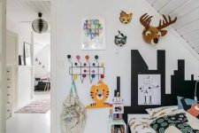 a small kid’s room with a black bed with colorful bedding, a gallery wall, a colorful polka dot floor and a plane