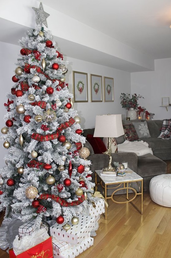 a snowy Christmas tree with gold and red ornaments, plaid ribbons and a silver tree topper