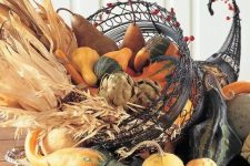 a statement Thanksgiving centerpiece made of a metal cornucopia centerpiece with vegetables, corn husks and wheat is a fab idea