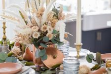 a stylish Thanksgiving tablescape with a neutral fresh and dried flower centerpiece with grass and greenery and some pears on the table