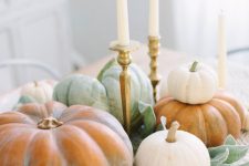 a super natural Thanksgiving centerpiece of various natural pumpkins, foliage and tall and thin candles in elegant candlesticks