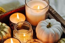 a tray with candles in jars and neutral and gold glitter pumpkins is a gorgeous and very easy decoration for Thanksgiving